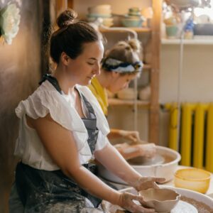 Two women creating handmade pottery in a cozy indoor studio setting.